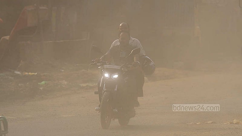 ঢাকা-নারায়ণগঞ্জ মহাসড়কে ধুলার মধ্যে মোটারসাইকেলে দুই জন। ধুলার পরিমান এতটাই যে দূর থেকে তাদের ভালো করে দেখাও যায় না