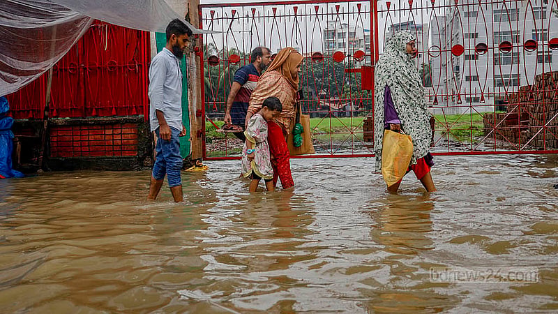 ঢাকার মিরপুর ১০ নম্বরে রোববার সকালের টানা বৃষ্টিতে ডুবে যায় সড়ক। ফলে হাঁটু পানি মাড়িয়ে চলাচল করতে হয় পথচারীদের