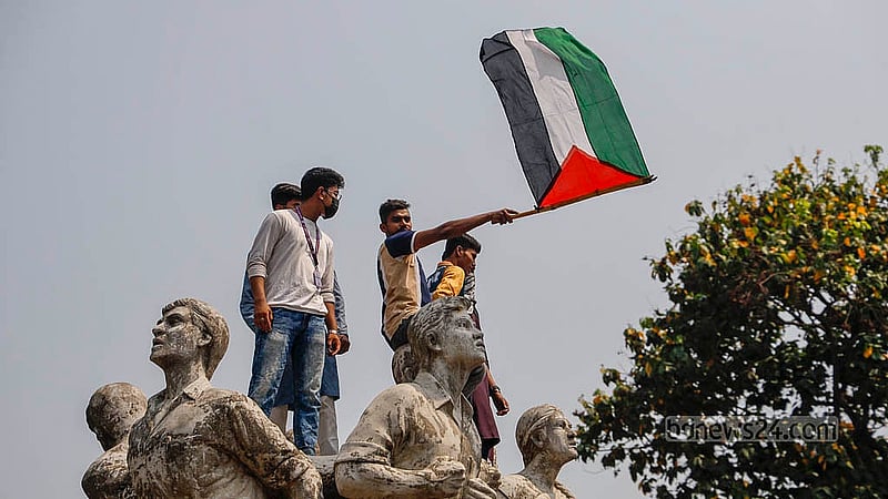 ঢাকা বিশ্ববিদ্যালয়ের রাজু ভাস্কর্যের সোমবার দুপুরে ফিলিস্তিনের পতাকা হাতে একজন