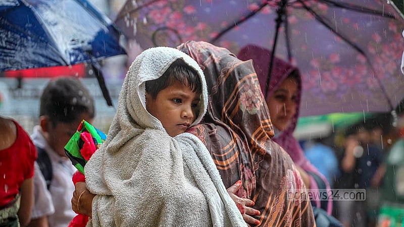 ঢাকার মুগদায় মঙ্গলবার বৃষ্টির মধ্যে সন্তান কোলে নিয়ে গন্ত্যেবের পথে এক নারী