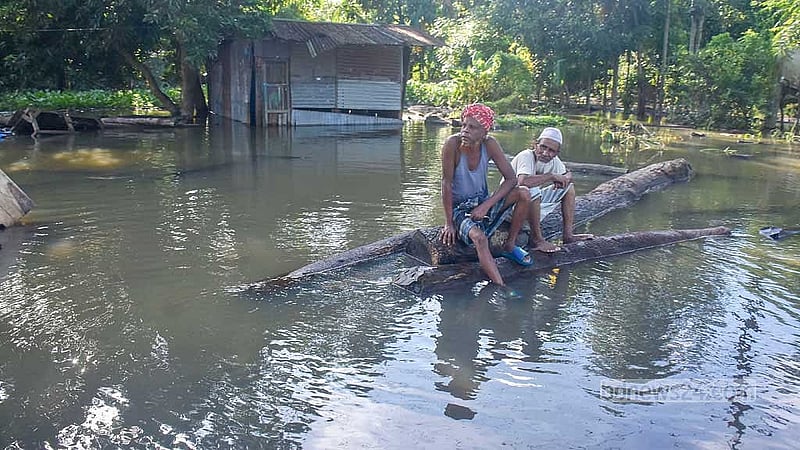 ফেনীর সোনাগাজীতে মঙ্গলবার বানের পানির মধ্যে জেগে ওঠা কাঠের গুঁড়িতে বসে অলস সময় পার করছেন দুই বয়োজ্যেষ্ঠ ব্যক্তি