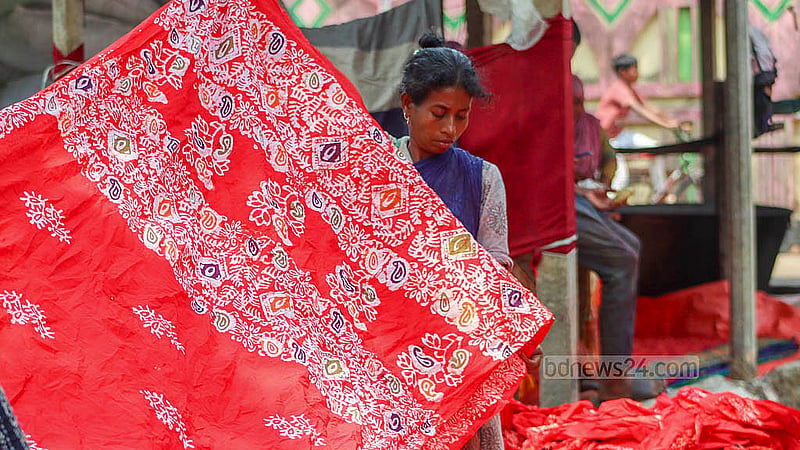 কুমিল্লার কমলপুরে রোদে বাটিক কাপড় শুকাতে দিচ্ছেন একজন। কুমিল্লার সদর উপজেলার কমলপুরে রয়েছে বেশ কয়েকটি বাটিক কারখানা