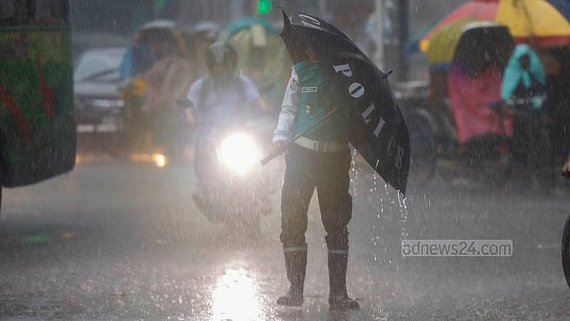 ঢাকায় মঙ্গলবার দমকা হাওয়ার মধ্যে ছাতা হাতে ট্রাফিক নিয়ন্ত্রণের কাজ করতে বেগ পেতে হচ্ছে এক পুলিশকে