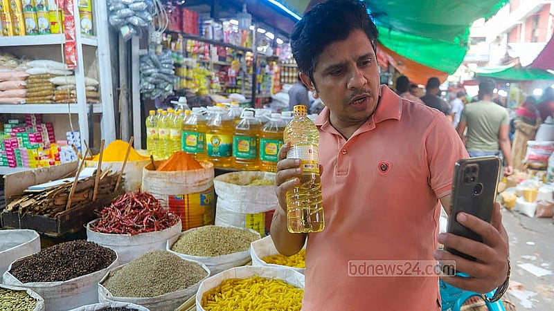 কারওয়ান বাজার থেকে সয়াবিন তেল কিনে পরিবারের সদস্যকে মোবাইল ফোনে দেখাচ্ছেন একজন। তার দুই লিটারের চাহিদা থাকলেও দোকানদার তাকে দিয়েছেন এক লিটার