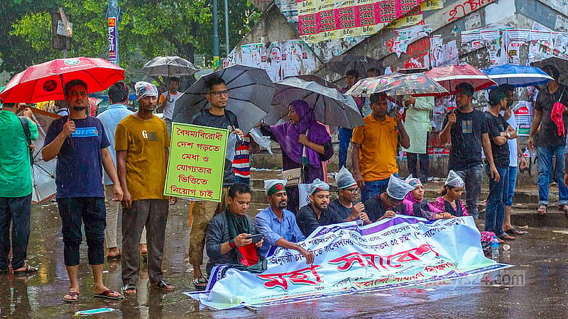 বৃষ্টির মধ্যেও সড়ক ছাড়েননি চাকরিপ্রত্যাশীরা; শনিবার দুপুরে শাহবাগ মোড়ে অবস্থান নিয়ে তারা বয়সসীমা বাড়ানোর দাবি জানান।