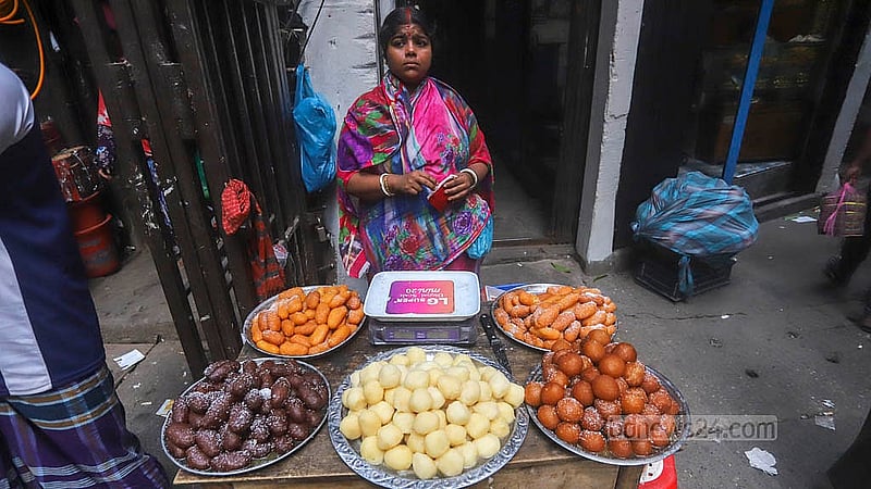 হালখাতা উপলক্ষে মিষ্টির চাহিদা বেড়ে যাওয়ায় পুরান ঢাকার তাঁতীবাজারের সড়কে পাশে বিক্রির জন্য মিষ্টি নিয়ে বসেছেন এক নারী