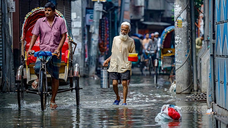 হাঁটু পর্যন্ত প্যান্ট গুটিয়ে পুরান ঢাকার বংশালের আব্দুল হাদী লেনে জমে থাকা নোংরা পানিতে খাবারের বাক্স নিয়ে যাচ্ছেন একজন