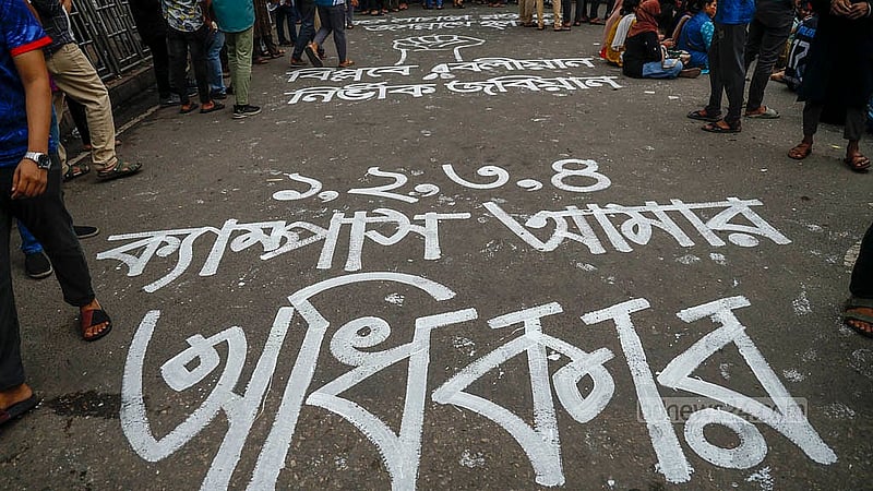 জগন্নাথ বিশ্ববিদ্যালয়ের আন্দোলনকারী শিক্ষার্থীরা অবস্থান কর্মসূচি চলাকালে সড়কে তাদের দাবি লিখে প্রতিবাদে অংশ নিয়েছেন
