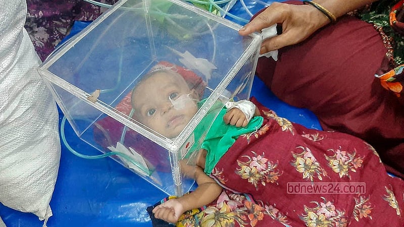 শ্বাসকষ্ট নিয়ে ৭ অক্টোবর নোয়াখালীর রামগতি থেকে ঢাকা মেডিকেল কলেজ হাসপাতালে ভর্তি হয়েছে ৩ মাসের শিশু খাদিজা। নিউমোনিয়া ধরা পড়ায় ওয়ার্ডে বেডের ওপর রাখা কাঁচের বাক্সের ভেতর মাথা রেখে অক্সিজেন দেওয়া হয় তাকে