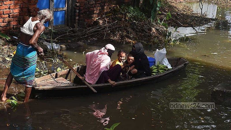 ফেনীর বিরলী বাজার রতনপুর গ্রামের নিচু এলাকায় এখনও কোমর সমান পানি। নৌকা দিয়ে নারীদের পার করছে এক বৃদ্ধ