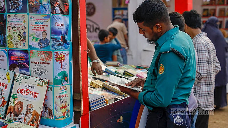 সোহরাওয়ার্দী উদ্যানে বইমেলায় দায়িত্ব পালনের এক ফাঁকে স্টলের সামনে দাঁড়িয়ে বই দেখছেন এক পুলিশ সদস্য