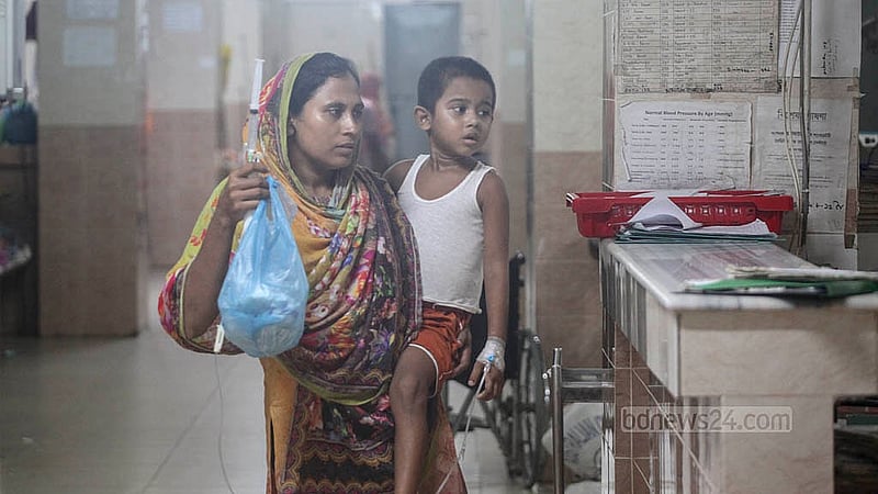 বাংলাদেশ শিশু হাসপাতাল ও ইনস্টিটিউটের ওয়ার্ডে মায়ের কোলে জ্বর ও শ্বাসকষ্ট আক্রান্ত এক শিশু। গরম-ঠান্ডায় এমন রোগী বেড়েছে হাসপাতালে