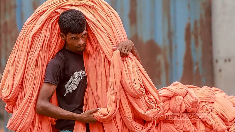 কারখানায় রং করার পর শুকানোর জন্য কাপড় খোলা মাঠে নিয়ে যান শ্রমিকরা। নারায়ণগঞ্জের ফতুল্লার হাজীগঞ্জ এলাকা থেকে তোলা