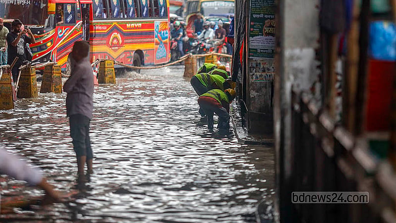 মিরপুর ১০ নম্বরে রোববার সকালে টানা বৃষ্টিতে ডুবে যাওয়া সড়কে ম্যানহোলের ঢাকনায় জমে থাকা ময়লা পরিষ্কারের কাজ করছেন ঢাকা উত্তর সিটি করপোরেশনের কর্মীরা
