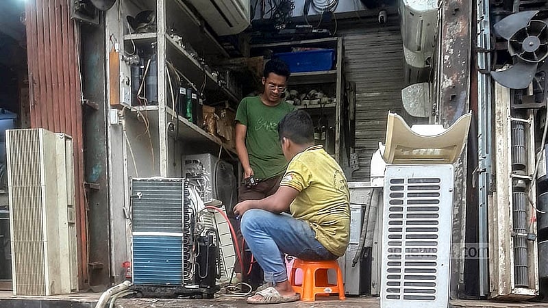 পুরান ঢাকার ধোলাইখালের পাঁচভাই ঘাট লেনে পুরনো এসি সার্ভিসিং করছেন একজন