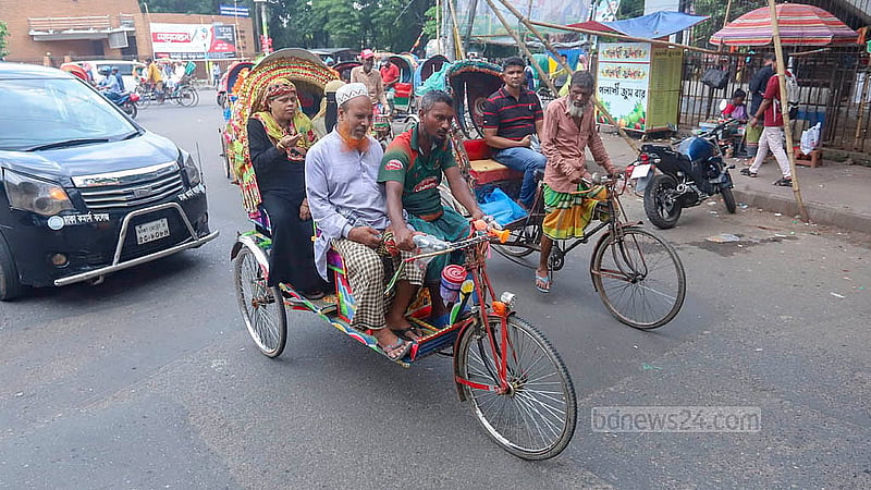 ব্যাটারির রিকশায় দুজন যাত্রীর পাশাপাশি সামনে চালকের পাশেও বসছেন একজন। ফলে অনেকটা বেঁকে রিকশার হ্যান্ডেল ধরে রাখতে হচ্ছে চালককে