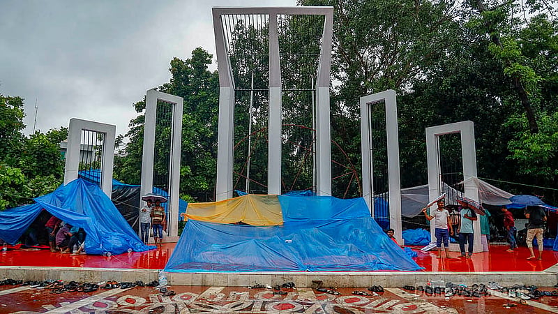 কেন্দ্রীয় শহীদ মিনারের সামনে অবস্থান কর্মসূচি পালন করছেন পল্লী বিদ্যুৎ সমিতির কর্মীরা। বৃষ্টির মধ্যে পলিথিন দিয়ে ছোট ছোট তাবু বানিয়ে তার নিচে অবস্থান করছেন