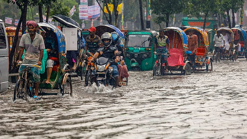 ঢাকায় শুক্রবার সকালের ঝুম বৃষ্টিতে নিউ মার্কেট সংলগ্ন হকার্স মার্কেটের সামনে সৃষ্ট জলজটের মধ্যেই চলছে রিকশা ও অটোরিকশা