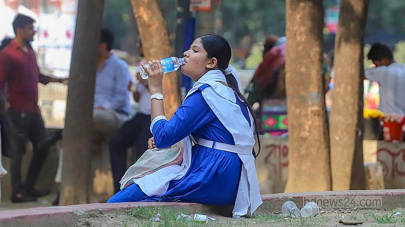 প্রচণ্ড গরমের মধ্যে ঢাকা বিশ্ববিদ্যালয় এলাকায় শনিবার গাছের ছায়ায় বসে পানি পান করতে দেখা যায় এক শিক্ষার্থীকে