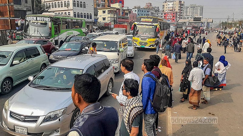 ঢাকার ধোলাইপাড় সড়ক বিভাজকে বাসের অপেক্ষায় মানুষ
