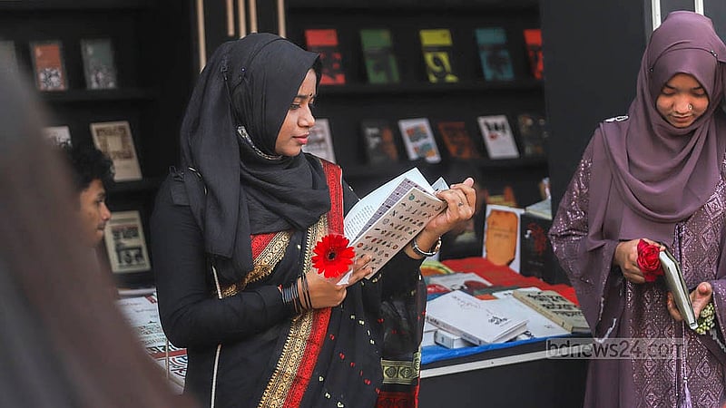 সোহরাওয়ার্দী উদ্যানে বইমেলায় বই দেখছেন এক তরুণী
