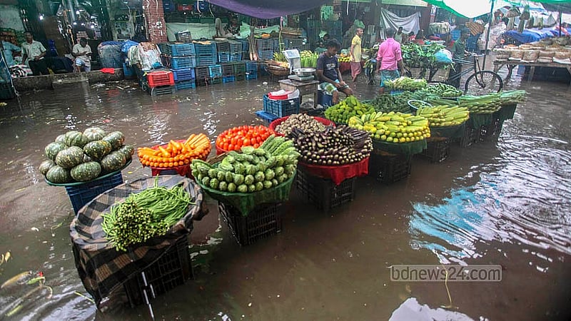 ঢাকার কারওয়ান বাজারে রোববার দুপুরের বৃষ্টিতে সবজির দোকান বসার জায়গা জলাবদ্ধ হয়। সড়ক তলিয়ে গেছে বৃষ্টির পানিতে