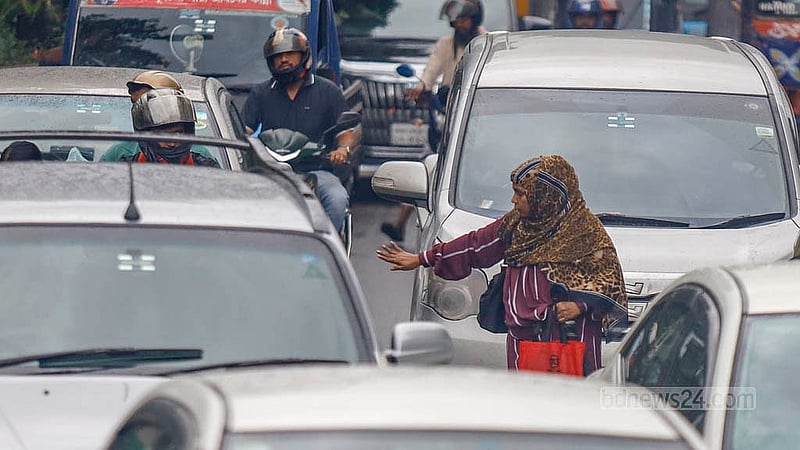 ঢাকার সোহরাওয়ার্দী মেডিকেল কলেজ হাসপাতালের সামনের ব্যস্ত সড়কের মাঝে এক নারীর হাতের ইশারায় গাড়ি থামিয়ে রাস্তা পারাপারের চেষ্টা