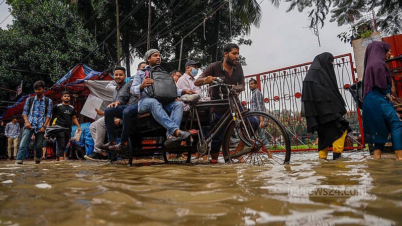 টানা বৃষ্টিতে রোববার ডুবে যায় ঢাকার মিরপুর ১০ নম্বরের সড়ক। ডুবে যাওয়া সড়কে মানুষ পারাপার করা হয় ভ্যানে
