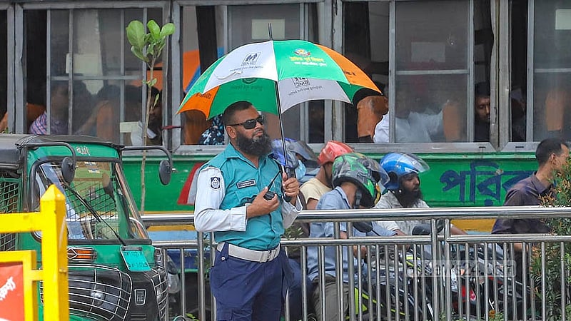 রোদ থেকে রক্ষা পেতে ছাতা নিয়ে দায়িত্ব পালন করছেন ট্রাফিক পুলিশ। শনিবার রাজধানীর কারওয়ান বাজার থেকে তোলা