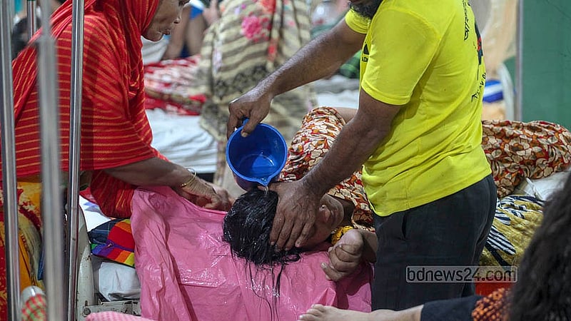 ঢাকার মুগদা জেনারেল হাসপাতালে ডেঙ্গু আক্রান্ত রোগীর মাথায় পানি ঢালছেন স্বজনরা