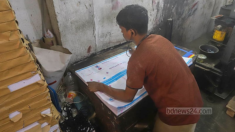 ঢাকার বাংলাবাজার প্যারীদাস রোডের একটি ছাপাখানায় এখনও চলছে বোর্ড বই ছাপানোর কাজ। ছাপা কাগজ ঠিক আছে কিনা, সেটিই যাচাই করছে একজন