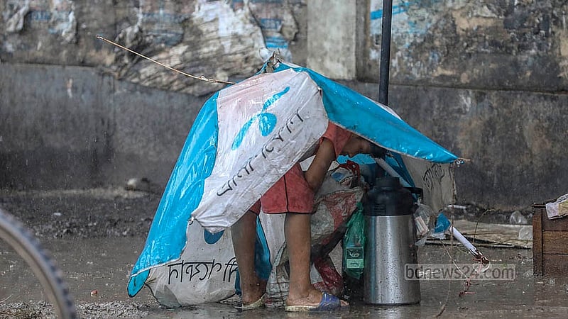 রাজধানীর মুগদা এলাকায় বৃষ্টির মধ্যে মাথা পলিথিনে মুড়ে নেয় শিশুটি