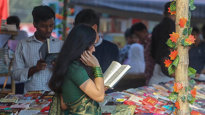 সোহরাওয়ার্দী উদ্যানে বইমেলায় বই দেখছেন এক তরুণী