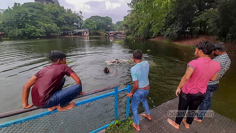 বৃষ্টির মধ্যে মঙ্গলবার রাজধানীর ধানমন্ডি লেকে গোসল করেন অনেকে