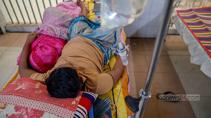 ঢাকার মুগদা মেডিকেল কলেজ হাসপাতালের বেডে ডেঙ্গু আক্রান্ত রোগী। পাশে শুয়ে আছেন রোগীর এক স্বজন