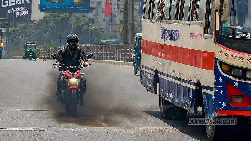 ঢাকার কাঁচপুর সেতুর ওপর দিয়ে কালো ধোঁয়া ছেড়ে চলছে বাস, সেই ধোঁয়ার মধ্যে দিয়ে মোটরসাইকেল চালিয়ে যাচ্ছেন একজন