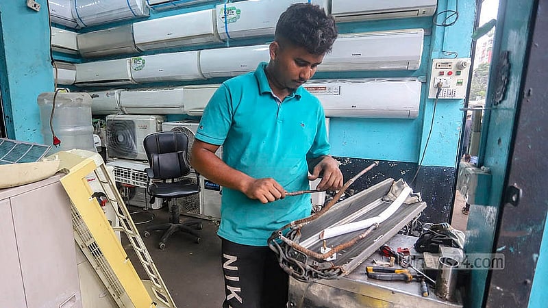 পুরান ঢাকার ধোলাইখালের পাঁচভাই ঘাট লেনে পুরনো এসি সার্ভিসিং করছেন একজন