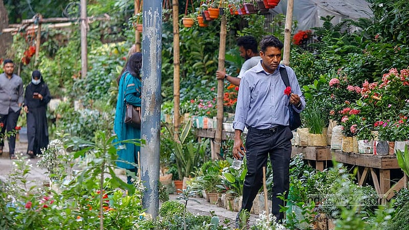 ফুটপাতের এক অংশজুড়ে নানান গাছের সমাহার। এর পাশ দিয়ে রয়েছে হাঁটার জায়গা। সেখানে গাছের পরিচর্যায় ব্যস্ত এক দোকানি