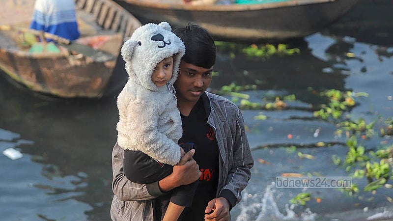 সকাল থেকে ঠান্ডা বেশি অনুভূত হওয়ায় শিশুকে গরম কাপড়ে জড়িয়ে বুড়িগঙ্গা নদী পার হয়ে রাজধানীতে আসেন একজন