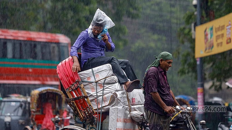 ঢাকা বিশ্ববিদ্যালয় এলাকায় বৃহস্পতিবার বৃষ্টির মধ্যে পণ্যবোঝাই রিকশায় পলিথিন মাথায় দিয়ে বসে আছেন এক ব্যক্তি