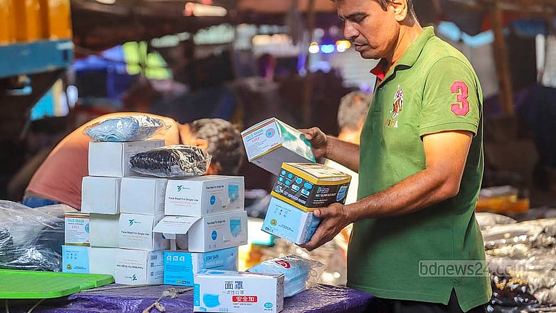 রাজধানীর বাবুবাজার ব্রিজের নিচের পাইকারি বাজার থেকে মাস্ক কিনে নিয়ে যাচ্ছেন অনেকে। কোভিড সংক্রমণ নতুন করে বাড়ার খবরে বেড়েছে চাহিদাও
