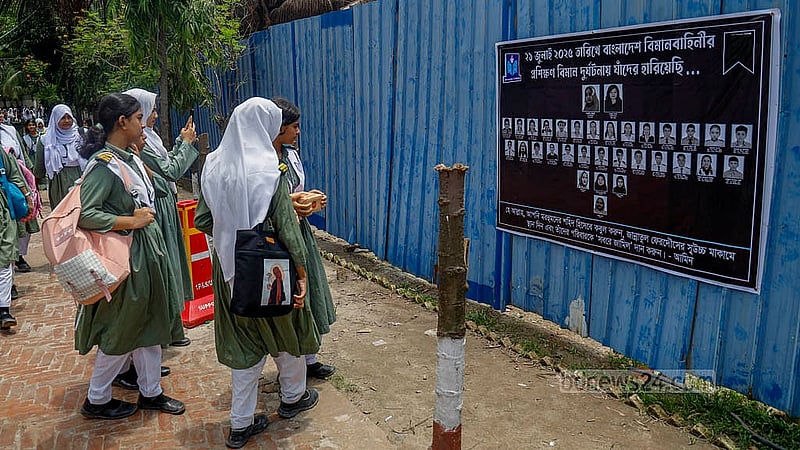 উত্তরায় মাইলস্টোন স্কুলের ক্যাম্পাসে বিমান বিধস্তের ঘটনায় নিহতদের ছবিসহ ঘটনাস্থলে লাগানো ব্যানার দেখছেন শিক্ষার্থীরা