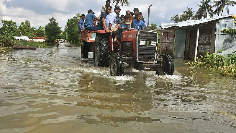 বন্যায় ফেনীর বিরলী বাজার এলাকার সড়ক এখনও ডুবে রয়েছে পানিতে; এর মধ্যেই ট্রাক্টরে করে যাচ্ছে মানুষ
