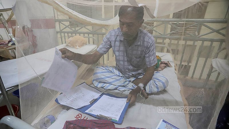 রাজধানীর মুগদা মেডিকেল কলেজ হাসপাতালের বেডে বসে শনিবার ডেঙ্গু আক্রান্ত এক রোগী দেখছেন তার রোগ পরীক্ষার প্রতিবেদন