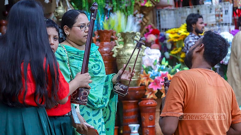 পহেলা বৈশাখ উদযাপনে দোয়েল চত্বরের দোকানগুলো থেকে হাতে তৈরি একতারা কিনছেন শিশুসহ অনেকে