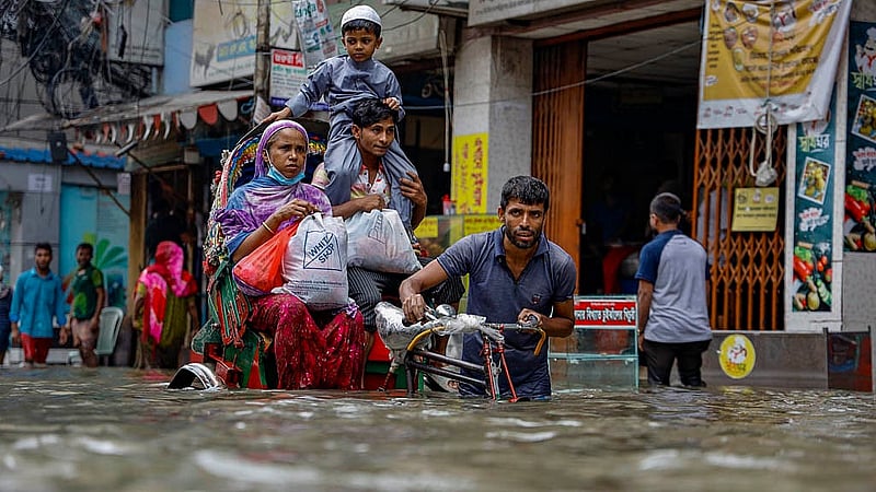 ঢাকার গ্রিন রোডে শুক্রবার সকালের বৃষ্টিতে জলাবদ্ধতার মধ্যেই গন্তব্যে ছোটেন অনেকে; রিকশায় বসে শিশুকে কাঁধে তুলে রাখেন এক ব্যক্তি