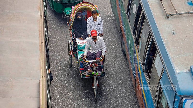 ঢাকার সায়েন্স ল্যাবরেটরি মোড়ে দুই বাসের মাঝখান দিয়ে চলছে ব্যাটারি রিকশা। অথচ মূল সড়কে এসব রিকশা চলাচলে রয়েছে নিষেধাজ্ঞা