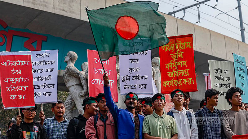 পাঠ্যবই থেকে ‘আদিবাসী’ লেখা চিত্রকর্ম বাদ দেওয়ার প্রতিবাদে বুধবার ঢাকা বিশ্ববিদ্যালয়ের রাজু ভাস্কর্যের সামনে ফেস্টুন হাতে আদিবাসী শিক্ষার্থীরা