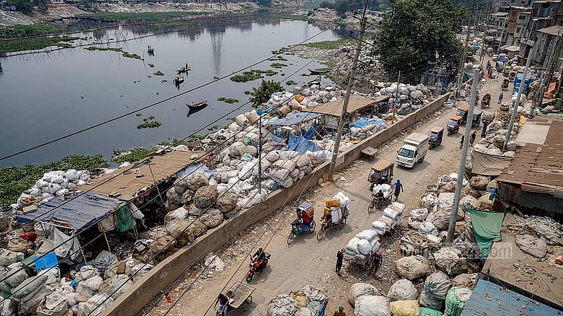 বুড়িগঙ্গার আদি চ্যানেলের পার ধরে সারি সারি ফেলে রাখা হয়েছে প্লাস্টিকের বস্তা, যার মধ্যে রয়েছে বিভিন্ন প্লাস্টিক ও ইলেকট্রনিক বর্জ্য। এগুলো বাছাই করে ভেঙে রিসাইক্লিংয়ের মাধ্যমে তৈরি হয় ছোটদের খেলনা সামগ্রী
