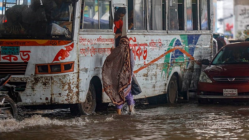 টানা বৃষ্টিতে ডুবে যাওয়া সড়কে বাসে ওঠার জন্য দৌড়াচ্ছেন এক নারী। রোববার মিরপুর ১০ নম্বর মেট্রো রেল স্টেশনের নিচ থেকে তোলা